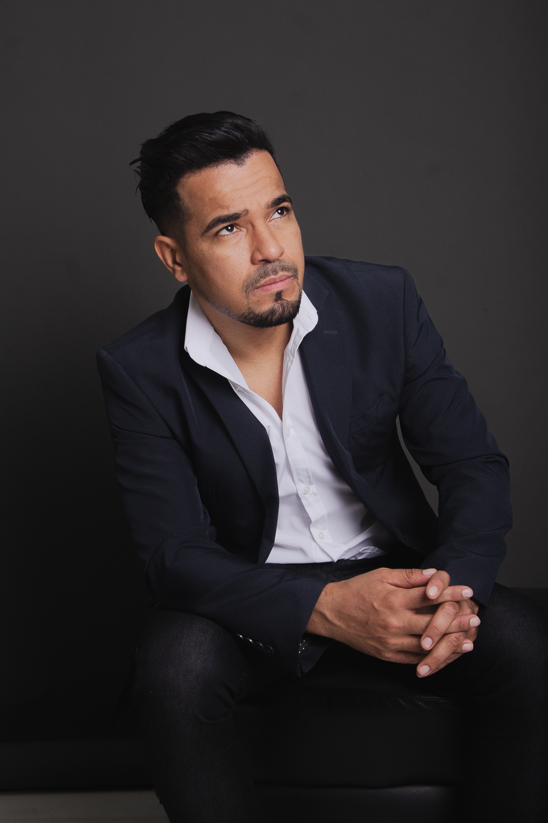Junior Rodrigues sentado, usando blazer